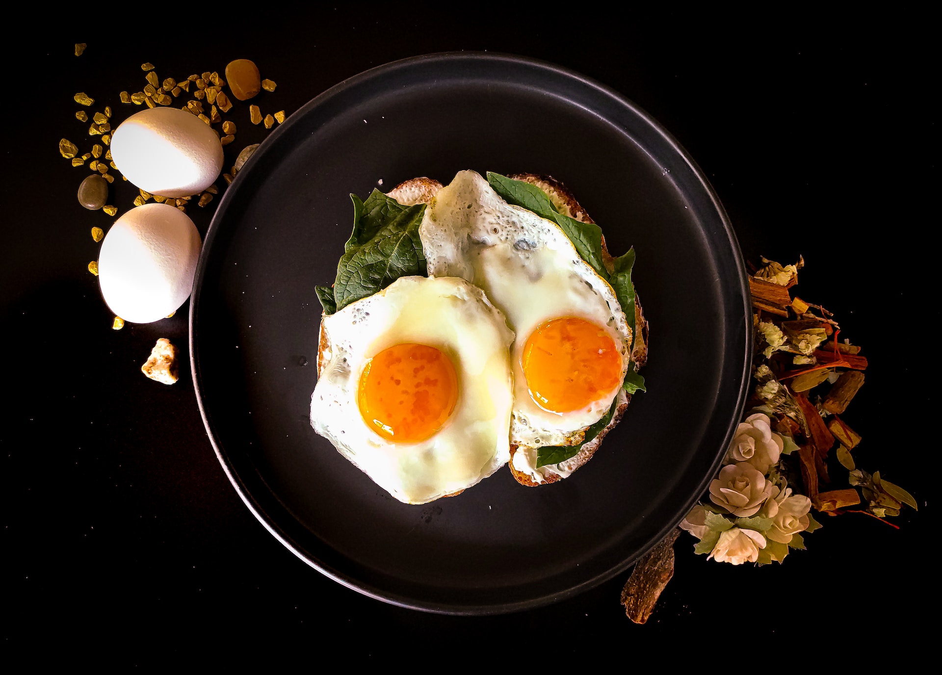 Fried eggs in a pan garnished and surrounded by raw eggs